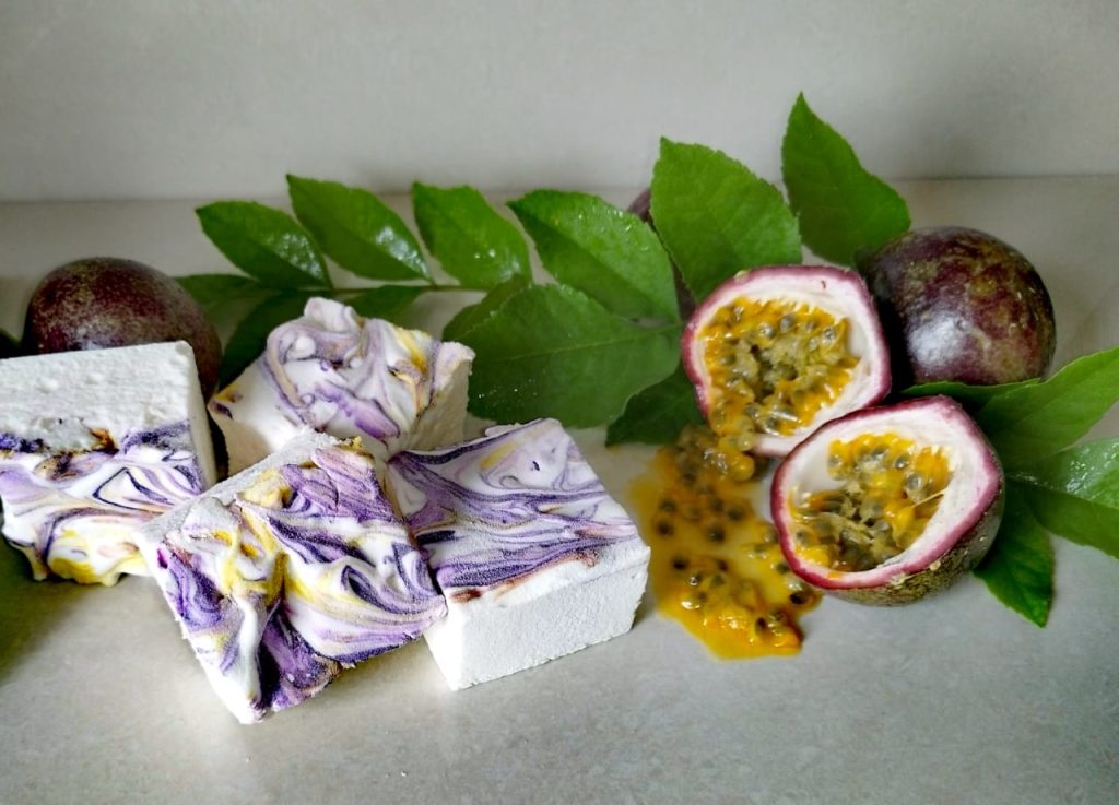 Passion fruit marshmallows marbled purple and gold beside fresh granadillas
